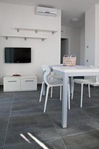 托尔博莱Casa Rosa dei Venti的白色的用餐室配有白色的桌椅