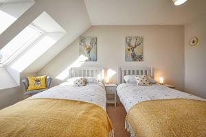 锡豪西斯Host & Stay - Sunflower Cottage的阁楼卧室设有两张床和窗户。