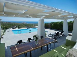 皮尔戈斯Christou Estate & Villas的一个带桌椅的庭院和一个游泳池