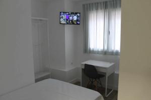 马德里Hostal royal begoña的一间卧室配有一张床、一张桌子和一台墙上的电视