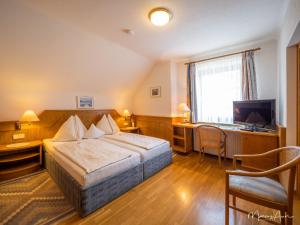金德贝格Pension Ehrenfried - Hotel garni的酒店客房配有一张床、一张书桌和一台电视。