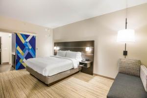 杰克逊维尔Holiday Inn Express & Suites Jacksonville - Town Center, an IHG Hotel的配有一张床和一把椅子的酒店客房