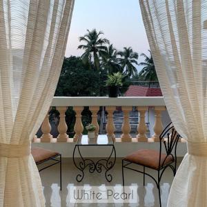 莫尔穆冈Vistara By The Beach Goa的阳台配有两把椅子和一张带窗帘的桌子
