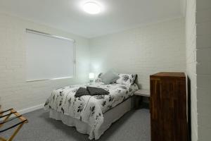 杰拉尔顿Apparition Apartments的白色的卧室设有床和窗户