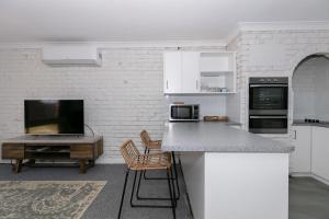 杰拉尔顿Apparition Apartments的白色的厨房配有柜台和桌子