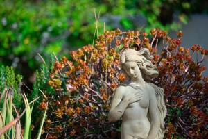 EsteponaEl Molino Estepona的站在灌木丛前的女孩雕像