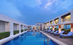 阿格拉Radisson Hotel Agra的酒店游泳池设有躺椅和遮阳伞