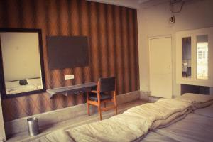 瓜廖尔Hotel Anand Palace的一间卧室配有一张床、一张书桌和一面镜子