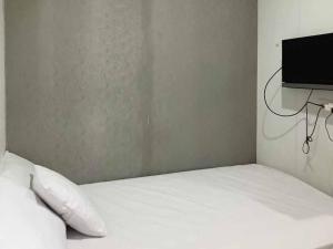 芝勒贡Aimer Guest House Syariah Mitra RedDoorz的卧室配有白色的床和平面电视。