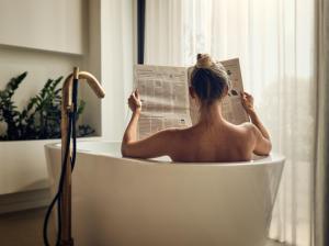 蒂锡利维Contessina Suites & Spa - Adults Only的坐在浴缸里读报纸的人
