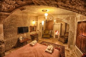 格雷梅旅行者洞穴宿舍酒店的一间设有床铺和一台电视的石墙客房