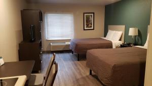 MerriamWoodSpring Suites Kansas City Mission的酒店客房带两张床和一张桌子以及椅子。