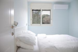 梅伦戈兰מקום בצפון הגולן的白色的卧室设有床和窗户