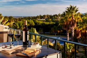 金塔湖Ancão Gardens的阳台上的桌子上放有一瓶葡萄酒和玻璃杯