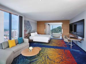 是拉差Novotel Marina Sriracha的酒店客房设有沙发、床和电视。