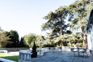 卡迪夫迈内尔派克酒店的庭院配有桌椅和树木
