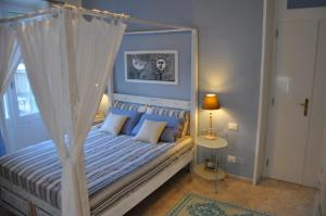 卡利亚里新罗曼蒂克公寓的卧室配有白色天蓬床和蓝色枕头