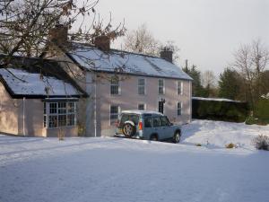 巴利米纳Lisnafillan Lodge的雪中停在房子前面的汽车