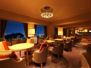 广岛广岛王子酒店的餐厅设有桌椅和大窗户。