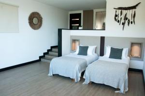 康塞普西翁Pura Lodge的一间卧室设有两张床,墙上设有一面镜子
