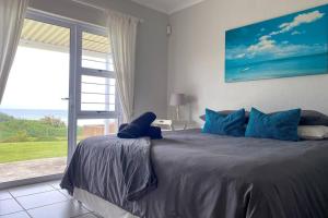 爱德华港Tamassa Holiday Home on the Beach, in Port Edward的一间卧室设有一张大床和大窗户
