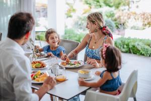 帕福斯Sofianna Resort & Spa的坐在餐桌旁吃食物的家庭