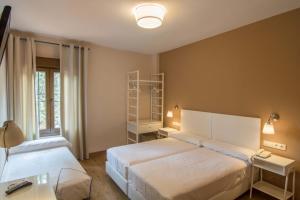 托莱多络丝思加雷斯酒店的一间卧室设有两张床、一张桌子和一个窗口