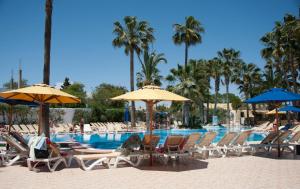 哈马马特Hotel Nesrine Hammamet的一组椅子和遮阳伞,位于游泳池旁