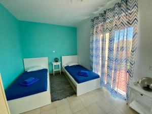 AsprouliánoiVilla Viva的配有两张床铺的蓝色墙壁和窗户