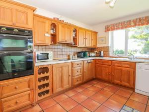 霍利黑德Charming 2 Bed House near Rhoscolyn DISCOUNTS FOR的厨房配有木制橱柜和瓷砖地板。