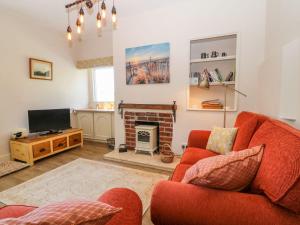 霍利黑德Charming 2 Bed House near Rhoscolyn DISCOUNTS FOR的客厅设有红色的沙发和壁炉