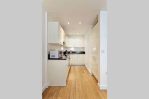 斯劳MODERN APARTMENT at SLOUGH STATION, LONDON IN 18 MINS!的厨房配有白色橱柜和硬木地板。