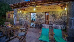 克鲁兹·德·特赫达Casa Rural Cottage Bentayga的一个带桌椅的庭院和一座石头建筑