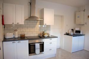 诺里奇Wensum Cottage的厨房配有白色橱柜和炉灶烤箱。