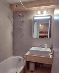 阿沃里亚兹STUDIO CABINE COSY TRÈS CALME RÉSIDENCE ALPAGES 2 AU PIED DES PISTES的一间带水槽、浴缸和镜子的浴室
