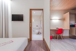 库里提巴Hotel Moov Curitiba的酒店客房,配有一张床和一张红色椅子