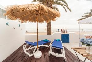 宏达海滩Luxury Suite Sea Front III的海滩甲板上的两把椅子和一把遮阳伞