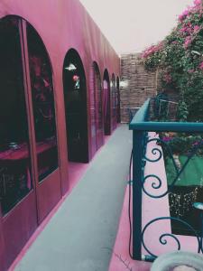 提兹尼特Riad Le Lieu的粉红色的建筑,有蓝色的栏杆和鲜花