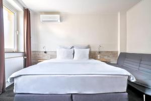 汉诺威威甘德设计酒店的卧室配有一张白色的大床和一张沙发。
