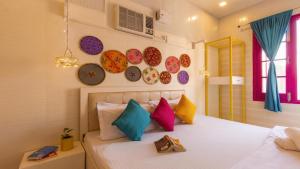 阿姆利则Madpackers Amritsar的卧室配有一张带色彩缤纷的枕头和盘子的床铺。