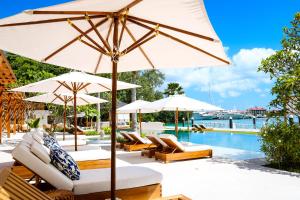 马埃岛L'Escale Resort Marina & Spa - Small Luxury Hotels of the World的游泳池旁的游泳池配有遮阳伞和躺椅