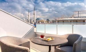 伊斯坦布尔Hotel Bossuite Business的阳台上的桌椅,上面放着一碗水果