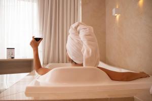 巴西利亚Cancún Hotel by H Hotéis - Airport的坐在浴缸里拿着一杯葡萄酒的女人