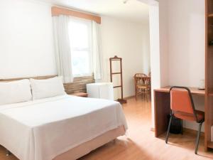 容迪亚伊Millian Hotel的一间卧室配有一张床、一张书桌和一个窗户。
