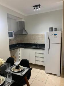 格拉玛多Apartamento Borges Gramado的厨房配有白色冰箱和桌椅
