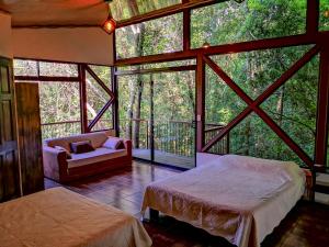 蒙泰韦尔德哥斯达黎加Quality Cabins Monteverde的一间带两张床的卧室和一张沙发,位于带窗户的房间内