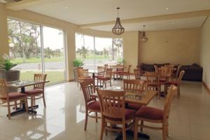 德班Regal Inn North Beach的餐厅设有木桌、椅子和窗户。