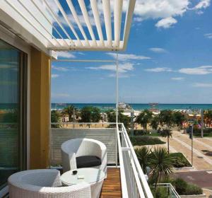 里乔内罗马酒店的阳台配有桌椅,享有海滩美景。