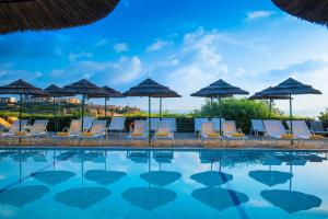 阿齐亚佩拉加蓝湾度假酒店的一组椅子和遮阳伞,位于游泳池旁