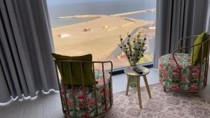 康斯坦察Maritimo Luxury ApartHotel的一间设有两把椅子的客房,享有海滩美景